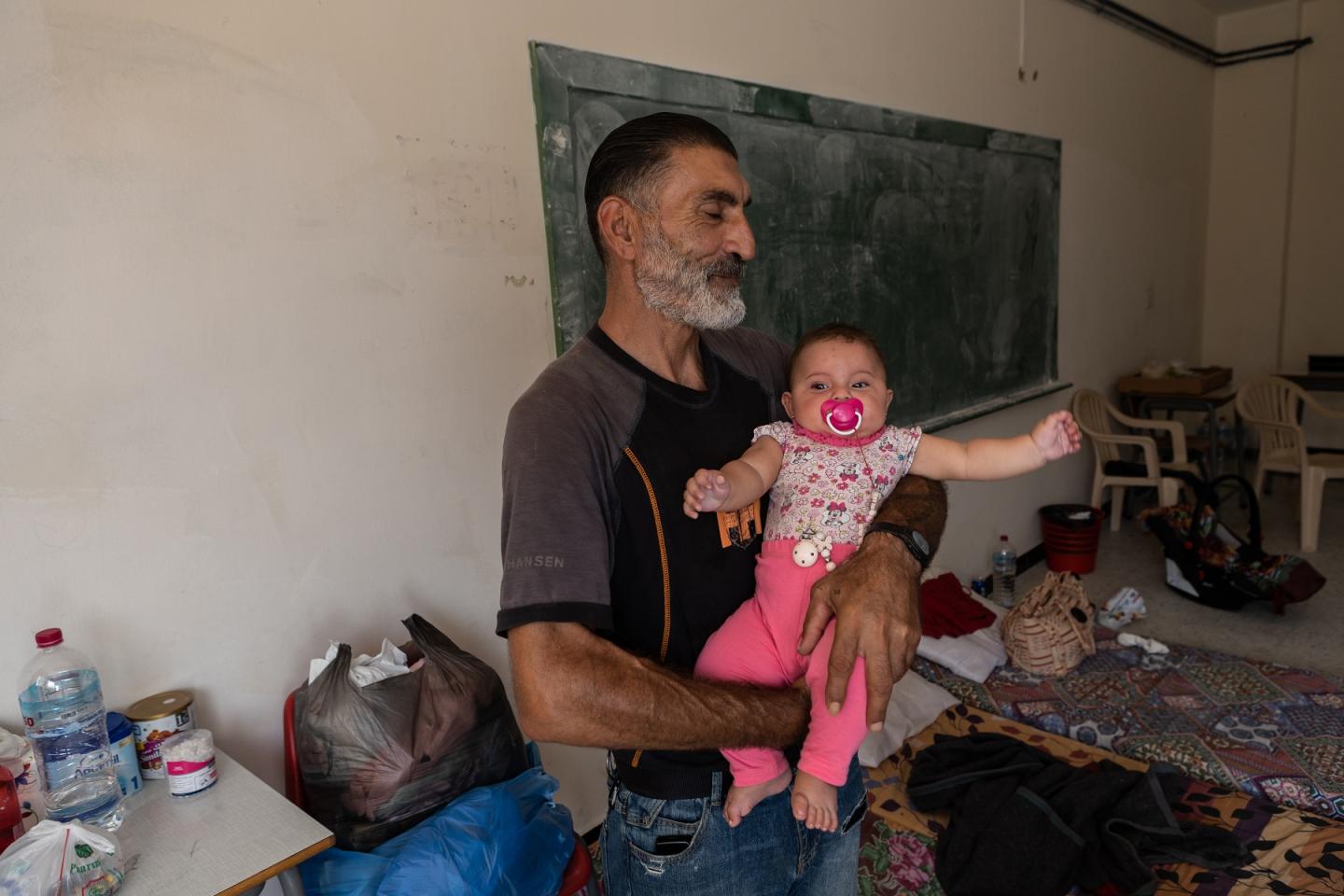 Joseph Kalakesh, 46 años, desplazado de Ramiah, con su bebé Fátima, de cinco meses, en brazos en una de las aulas de una escuela en Tiro, ahora convertida en refugio temporal. / M.M. 