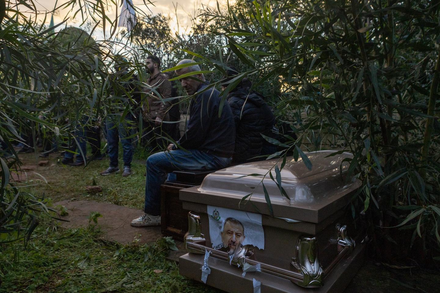 Dos hombres sentados sobre el ataúd de Saleh Al-Arouri, antes de ser enterrado en el cementerio “de los mártires” del campo de refugiados de Shatila, donde descansan figuras importantes de la resistencia palestina como el escritor Ghassan Kanafani. / M. M. 