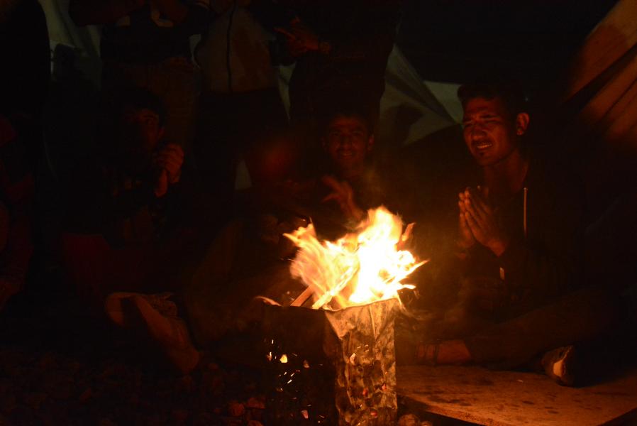 Refugiados tocando musica por la noche ante una hoguera en Katsikas.