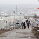 <p>Varias familias caminan entre los módulos prefabricados en los que viven los refugiados de origen sirio en Harmanli.</p> (: G.H.)