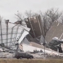 <p>Un coche pasa junto a restos de una nave destruida por el tornado en Edwardsville (Illinois, Estados Unidos).</p>