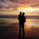 <p>Un hombre contempla el atardecer con su hijo en brazos. </p>