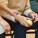 <p>Un anciano sostiene una pelota junto a una persona cuidadora.</p>