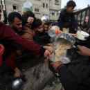 <p>Un grupo de hombres gazatíes se afanan por conseguir algo de comida durante el reparto. / <strong>Mahmoud Mushtaha</strong></p>