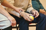 <p>Un anciano sostiene una pelota junto a una persona cuidadora.</p>