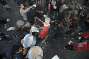 <p>Un grupo de hombres gazatíes se afanan por conseguir algo de comida durante el reparto. / <strong>Mahmoud Mushtaha</strong></p>