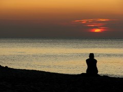 <p>Mujer en la playa durante la puesta de sol.</p>