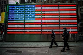 <p>Dos policías andando frente a la bandera de EE.UU</p>