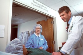 <p>Profesionales sanitarios con una paciente tras una operación.</p>