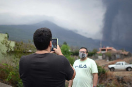 <p>Dos vecinos de La Palma se toman fotos con el volcán de fondo.</p>