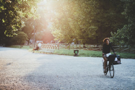 <p>Una mujer en bicicleta por un parque de Milán.</p>