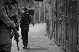 <p>Una niña palestina mira a un militar israelí de guardia en Cisjordania. <strong>/ Ariel Feldman </strong></p>