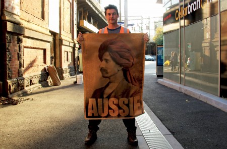 <p>Peter Drew posa junto a uno de los carteles con los que está empapelando Australia.</p>
