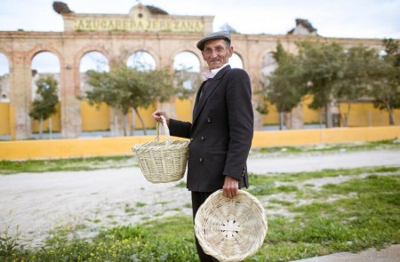 <p>Cristóbal Flores Valverde, el último gitano canastero, ante la antigua azucarera de El Portal y con sus canastos en las manos.</p>
