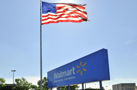 <p>Cartel de Walmart junto a una bandera de EE.UU</p>