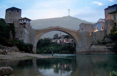 <p>El Puente Viejo de Mostar y, al fondo, la cruz levantada por las autoridades croatas en el monte desde donde sus tropas bombardeaban la ciudad.</p>