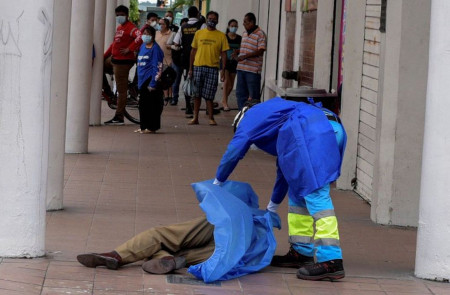 <p>Un sanitario cubre un cadáver en una calle de Guayaquil. </p>
