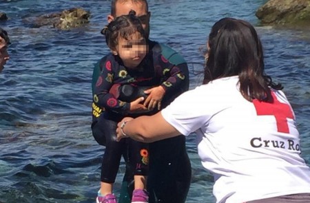 <p>Un buzo de la Guardia Civil con una menor en brazos y una trabajadora de la Cruz Roja en Ceuta.</p>