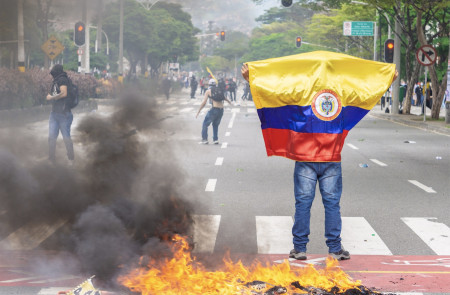 <p>Un hombre sujeta la bandera de Colombia en medio de los disturbios en el Paro Nacional (abril 2021).</p>