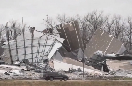 <p>Un coche pasa junto a restos de una nave destruida por el tornado en Edwardsville (Illinois, Estados Unidos).</p>