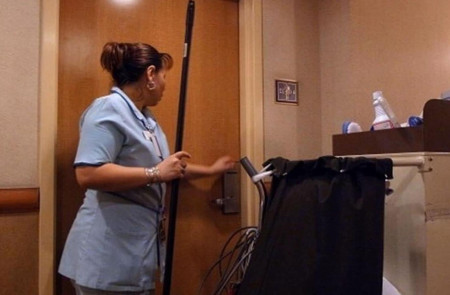 <p>Una camarera de piso entrando en una habitación para limpiar.</p>