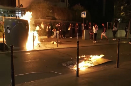 <p>En Francia, un grupo de manifestantes junto a un contenedor en llamas. / <strong>YouTube (DW Español)</strong></p>