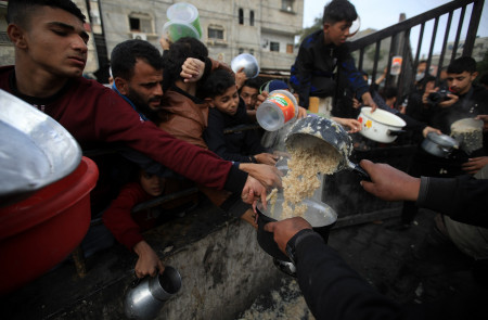 <p>Un grupo de hombres gazatíes se afanan por conseguir algo de comida durante el reparto. / <strong>Mahmoud Mushtaha</strong></p>