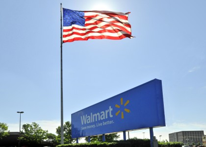 <p>Cartel de Walmart junto a una bandera de EE.UU</p>