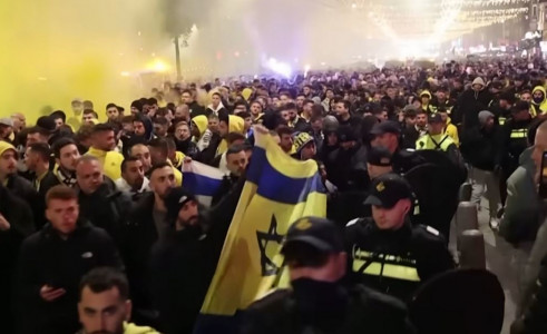 <p>Hooligans del Maccabi de Tel Aviv en Ámsterdam vigilados por la policía. / <strong>Michel van Bergen (Guardian News / Youtube)</strong></p>