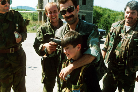 <p>Un comandante serbio pone una pistola en la cabeza de su hijo mientras él y sus amigos bromean a la esperan de un intercambio de prisioneros cerca de Sarajevo, en el verano de 1992. / <strong>Mikhail Evstafiev</strong></p>