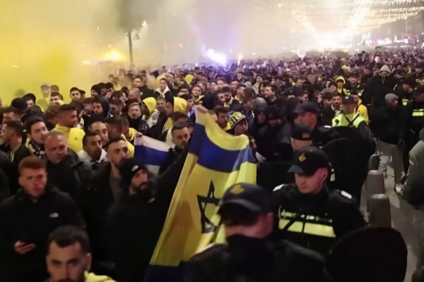 <p>Hooligans del Maccabi de Tel Aviv en Ámsterdam vigilados por la policía. / <strong>Michel van Bergen (Guardian News / Youtube)</strong></p>