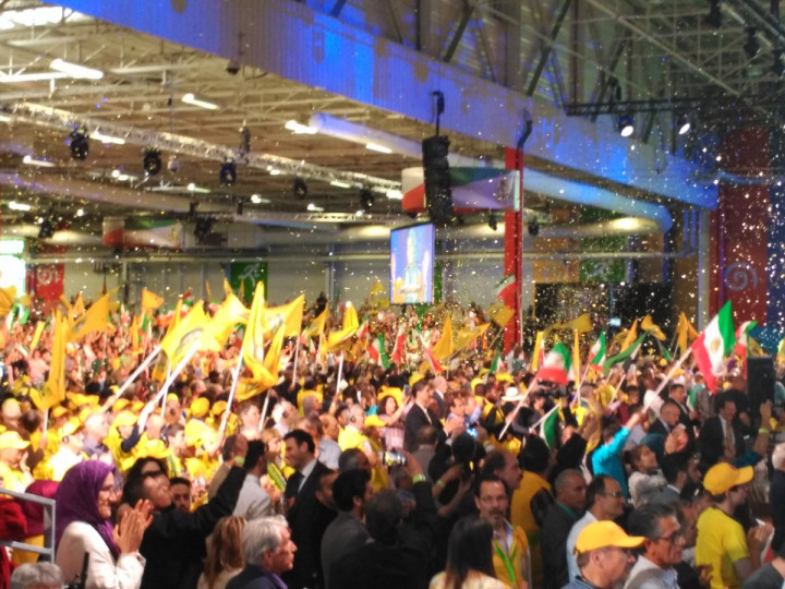 <p>Los asistentes al encuentro aplauden y alzan las banderas cuando aparece Maryam Rajavi.</p>