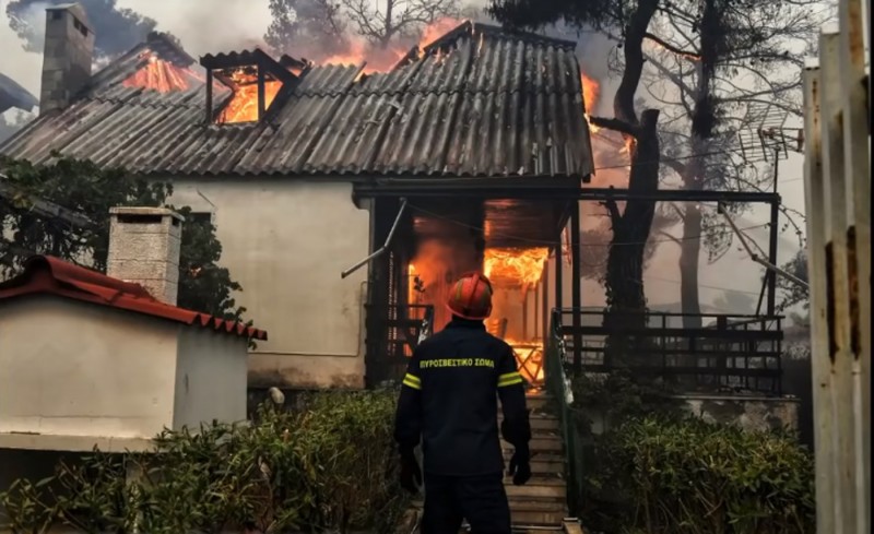 <p>Un bombero se acerca a una casa incendiada. 24 de julio de 2018, Grecia. </p>