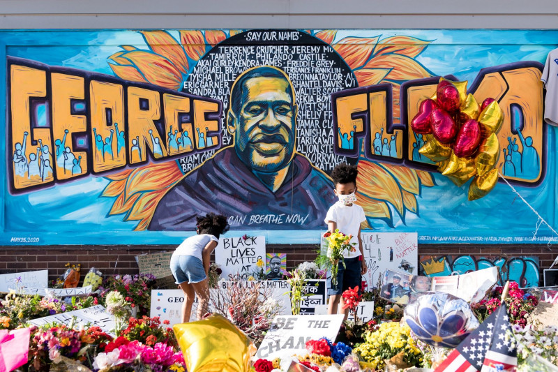 <p>Dos niños depositan flores en el memorial erigido a George Floyd en el lugar de su muerte. </p>