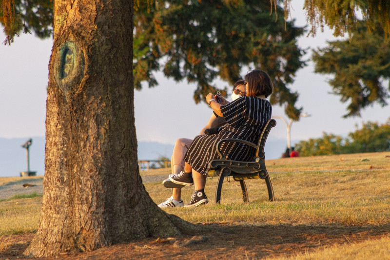 <p>Dos mujeres en un banco al aire libre.</p>