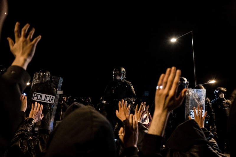 <p>Asistentes a un encuentro en defensa de la libertad de expresión en Madrid levantan las manos frente al cordón policial.</p>