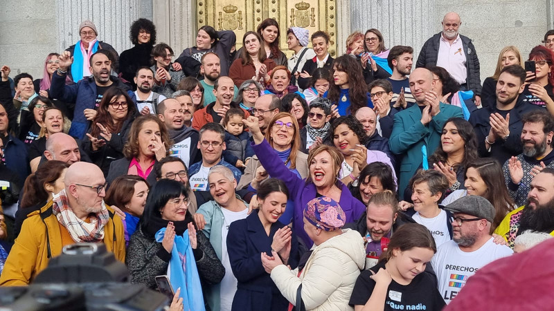 <p>Activistas trans celebran, junto a la ministra Montero, la aprobación de la ley, a las puertas del Congreso, el 22 de diciembre.</p>