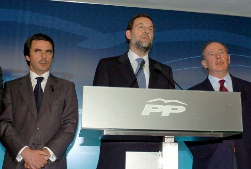 <p>Comparecencia de los líderes del PP durante la noche electoral de las elecciones generales de 2004. De izquierda a derecha, José María Aznar, el candidato Mariano Rajoy y Rodrigo Rato. /<strong> Wikipedia</strong></p>