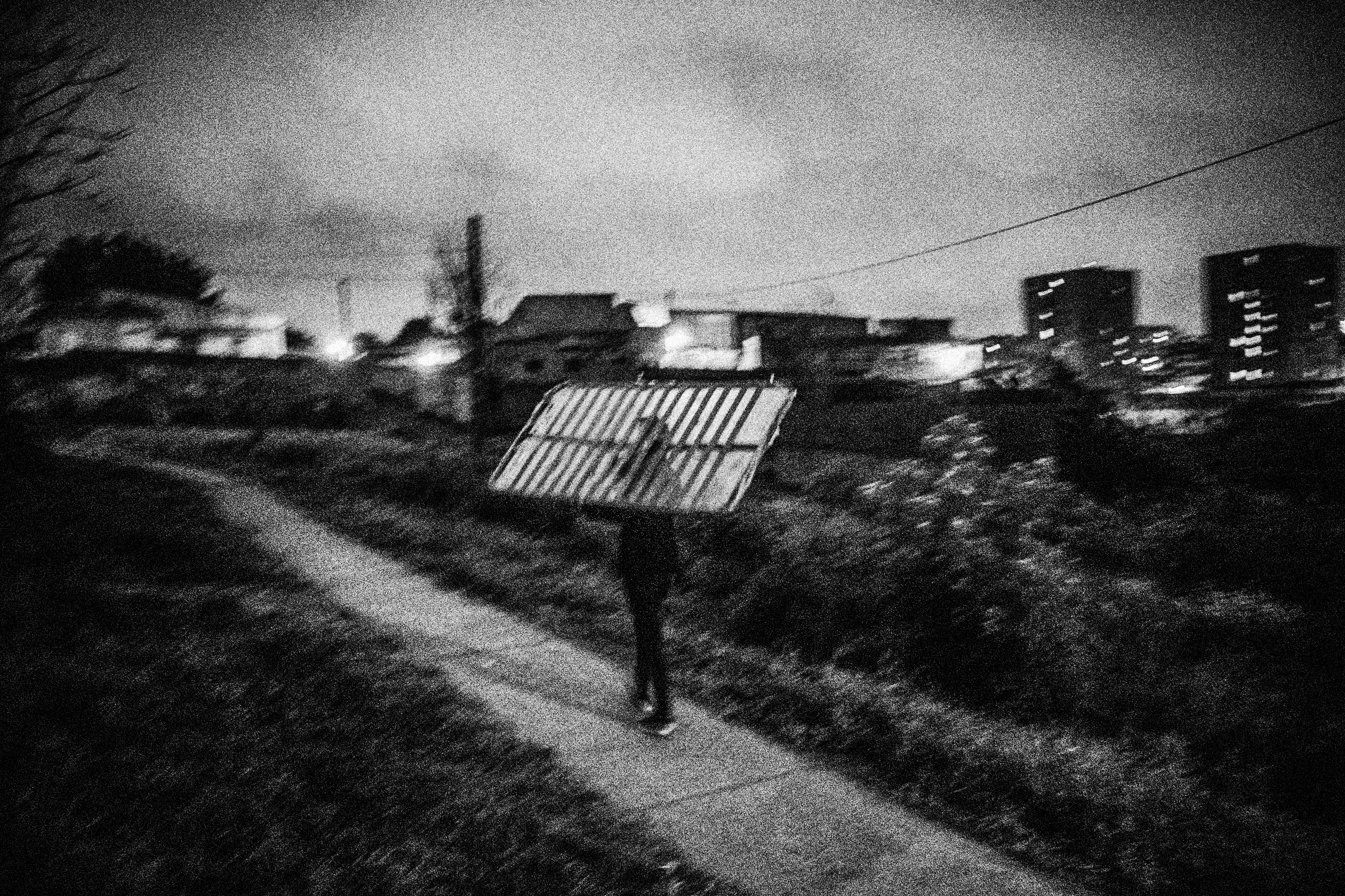 25 de marzo de 2014. Un hombre se dirige hacia su casa en un pueblo abandonado en Lisboa cargado con un cabecero que ha encontrado en la basura.