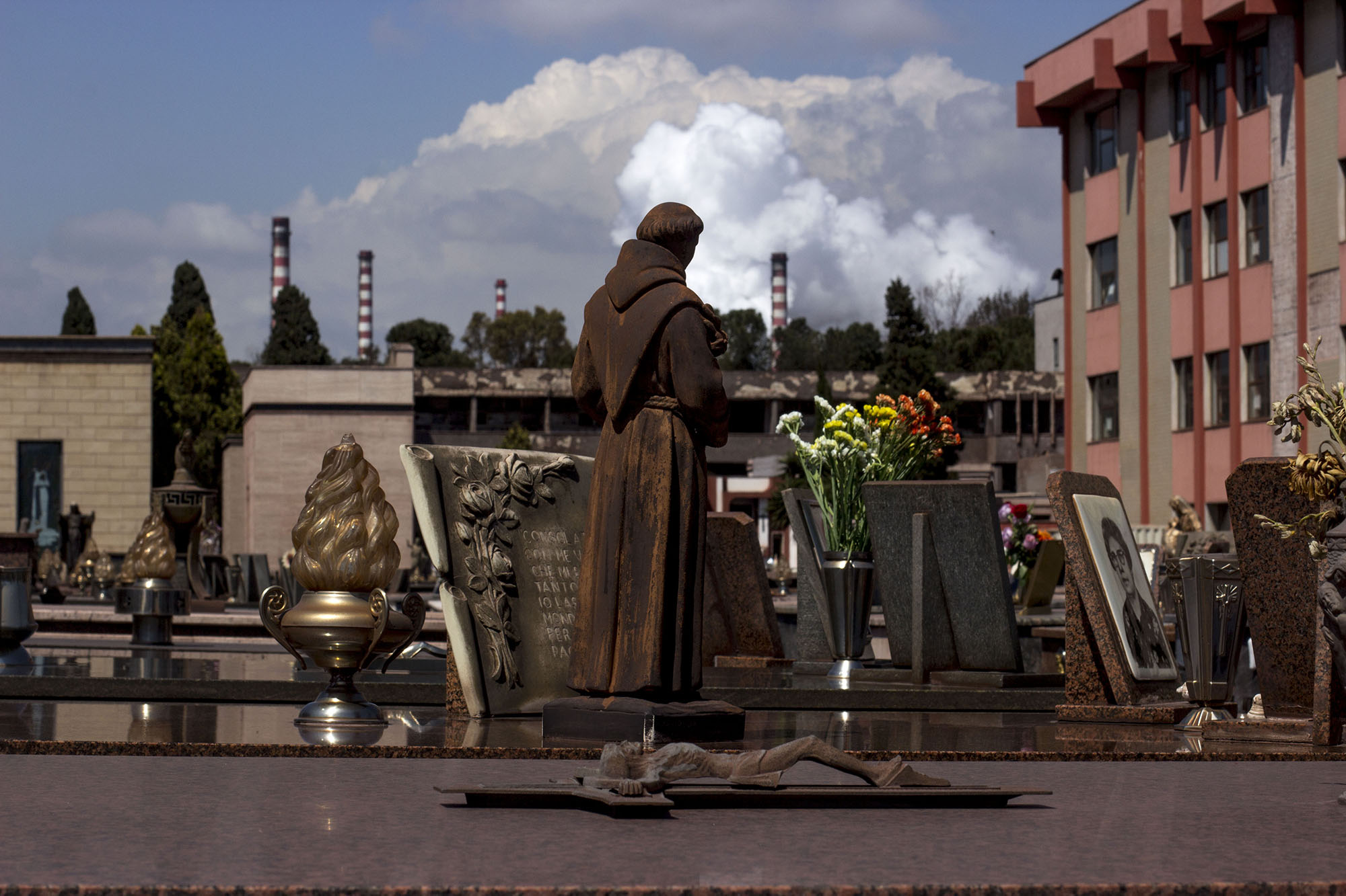 <p>Vista general del cementerio junto a las chimeneas de Ilva, la fábrica de acero.</p>