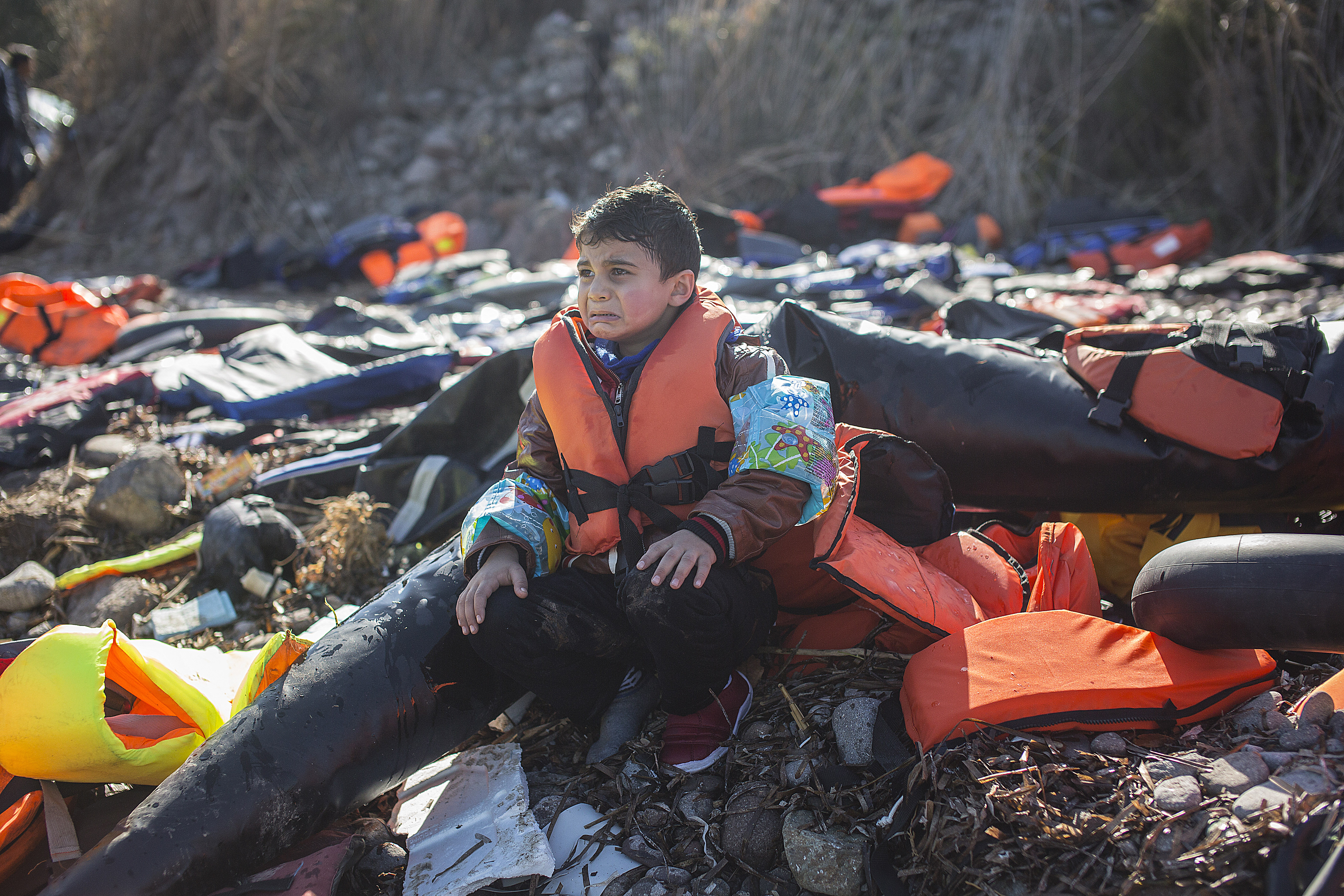 <p>Un niño sirio llora mientras espera a que sus padres salgan del bote en el que acaban de llegar a Europa. Por seguridad, las personas mayores y los niños son los primeros en desembarcar</p>