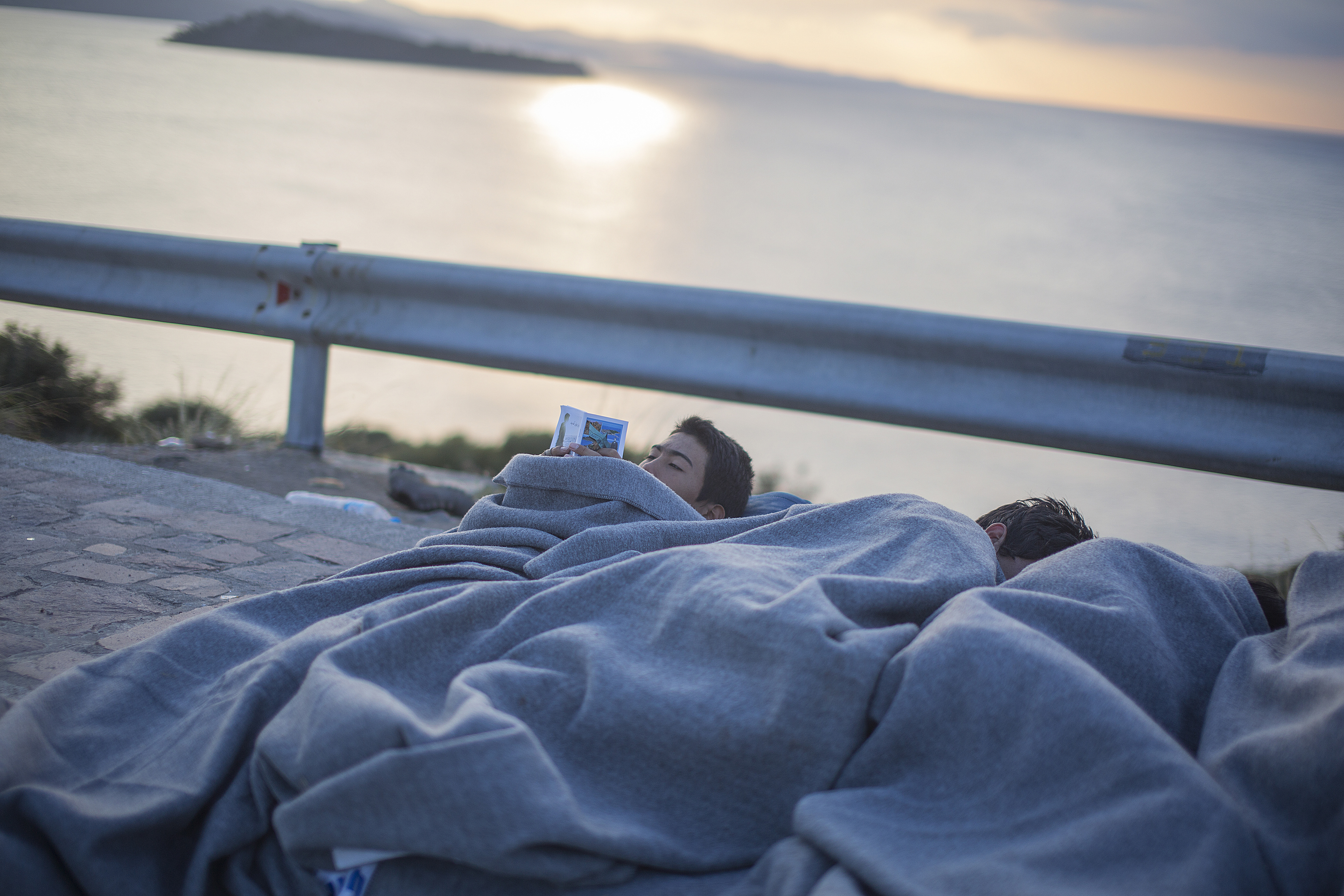 <p>Un joven lee junto a sus compañeros dormidos en Oxi, un campo de refugiados de tránsito cerca de Petra. A la mañana siguiente saldrán en autobús hacia Kara Tepe y Moria, los dos campos principales de Lesbos, cerca de Mitilene, la capital.</p>