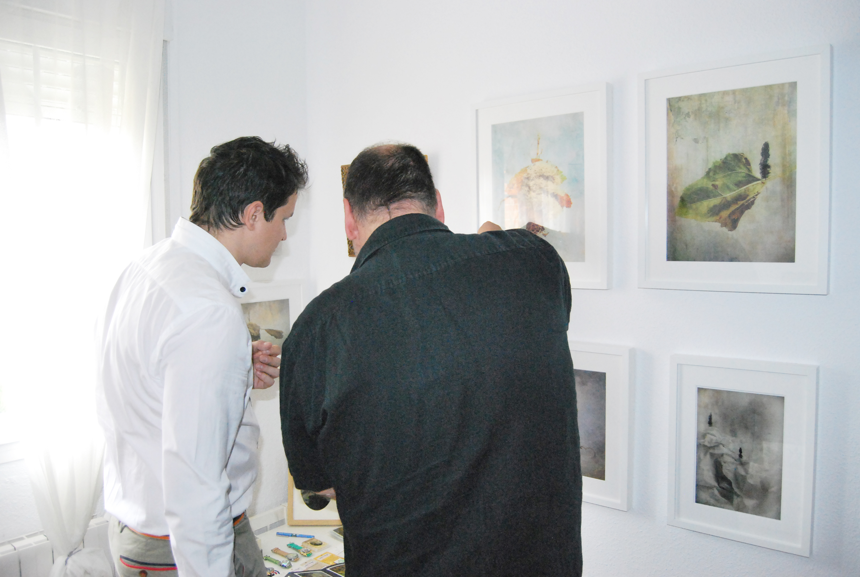 <p>José Luis Pérez Moral mostrando a un visitante obras de las series <em>El</em> <em>Viaje IOS.</em></p>
