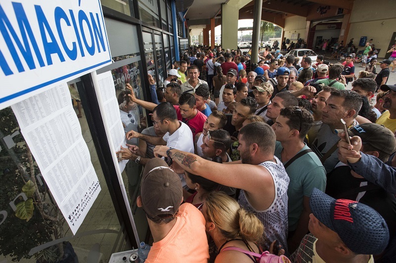 <p>Un grupo de cubanos mira las listas de los primeros afortunados que podrán volar en Estados Unidos. </p>