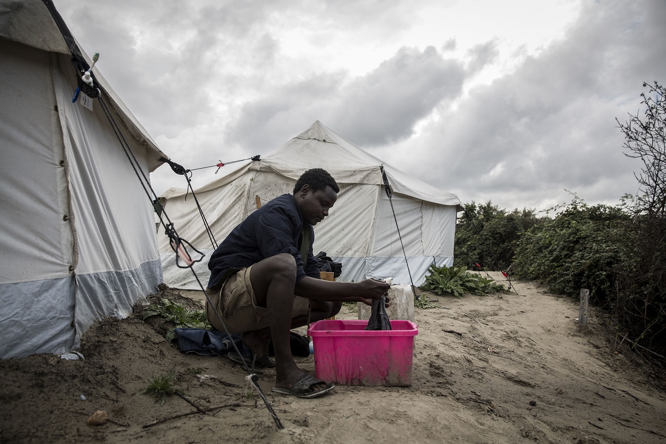 <p>Un migrante sudanés lava la ropa que ha usado durante toda la semana anterior. </p>