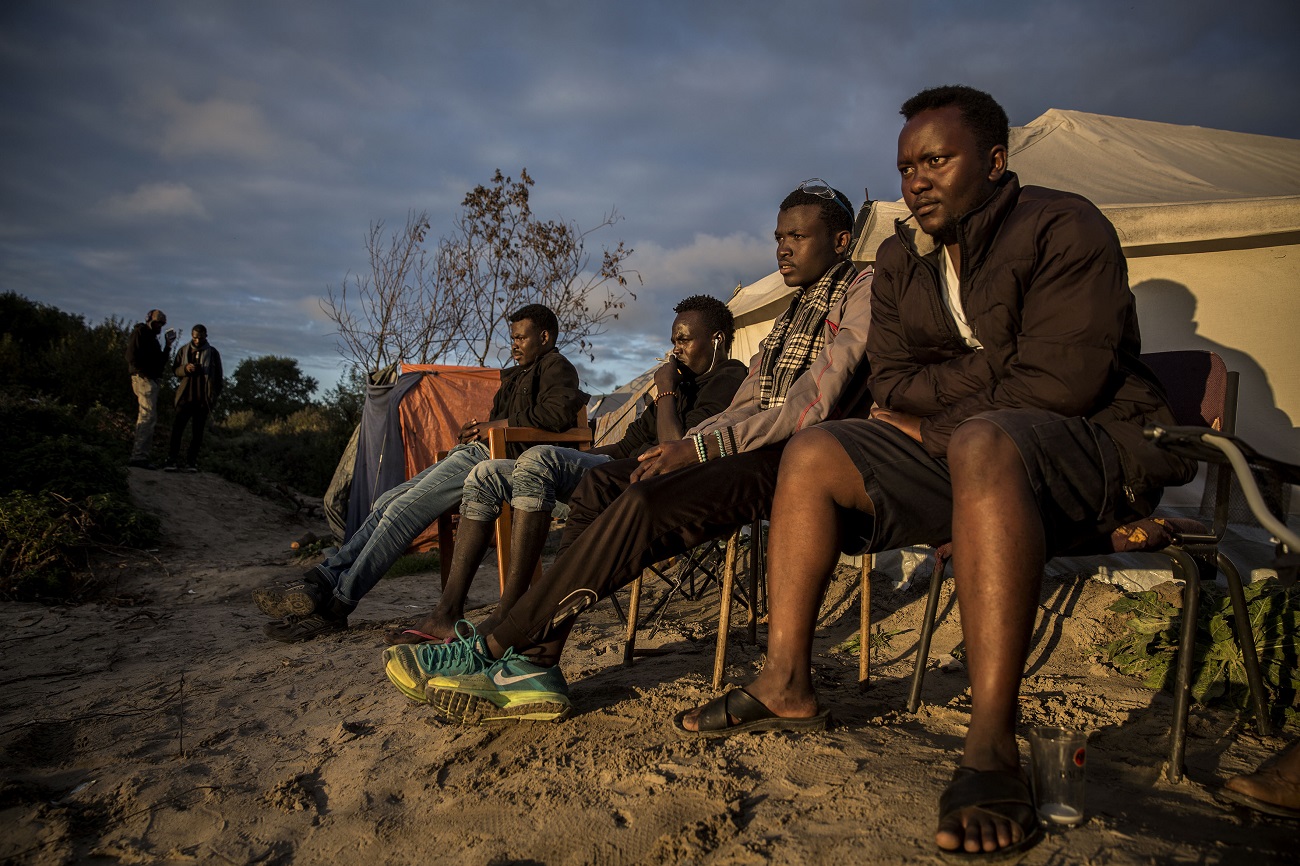 <p>Un grupo de jóvenes sudaneses observa como otros juegan al fútbol. </p>